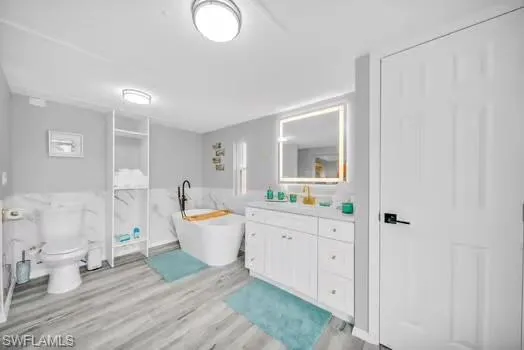Full bathroom with vanity, a freestanding bath, and light wood-style floors