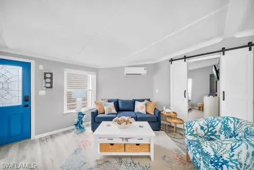 Living area with wood finished floors, a barn door, and an AC wall unit