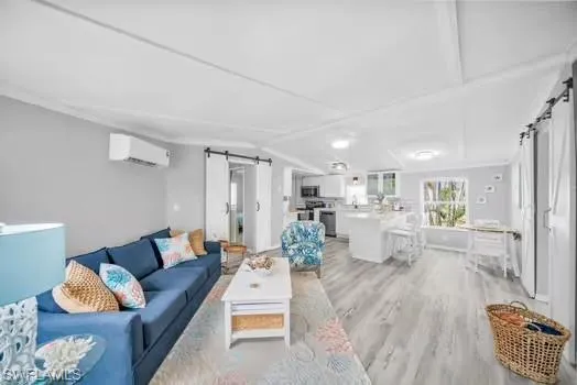 Living area with a barn door, light wood-type flooring, lofted ceiling, and a wall unit AC