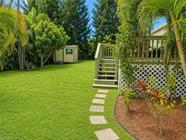 Expansive green lawn with a stepping stone pathway leading to a raised wooden deck