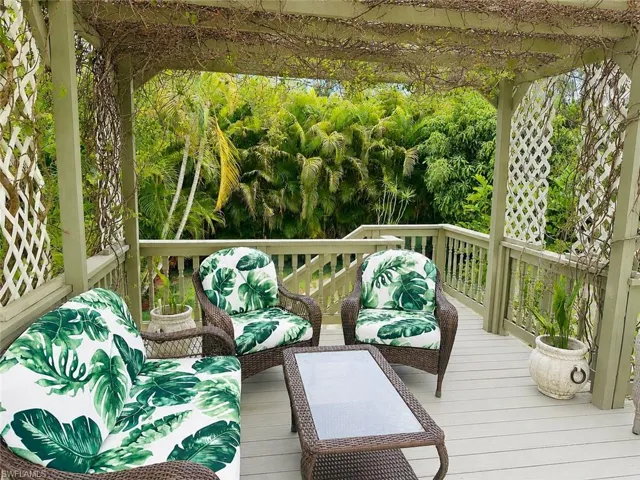 Expansive outdoor deck featuring a light-toned wood-finish surface, a substantial wooden pergola overhead, and white lattice panels