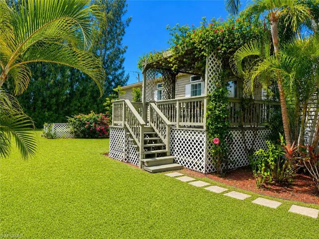 Wood-sided exterior featuring an elevated deck with a trellis and lush climbing vines