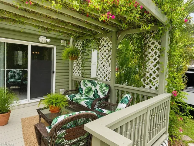 Outdoor patio featuring a pergola with mature vines and pink blossoms, wood-finish decking, and white lattice panels