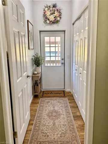 Entryway featuring wood-finish flooring, a paneled door with glass inserts, and white bi-fold closet doors