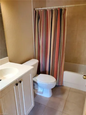 Full bathroom with shower / bath combination with curtain, vanity, toilet, and tile patterned floors