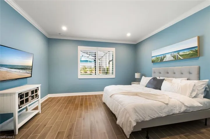 Bedroom featuring wood tiled floors, crown molding, and recessed lighting