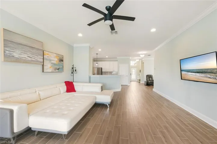 Living area featuring recessed lighting, wood tiled floors, ceiling fan, and crown molding