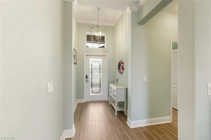 Foyer with tile floors, ornamental molding, suspended lighting, and a high ceiling