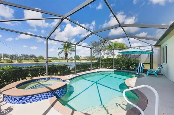 Integrated pool / hot tub featuring a sunroom, glass enclosure, a water view, and a patio area