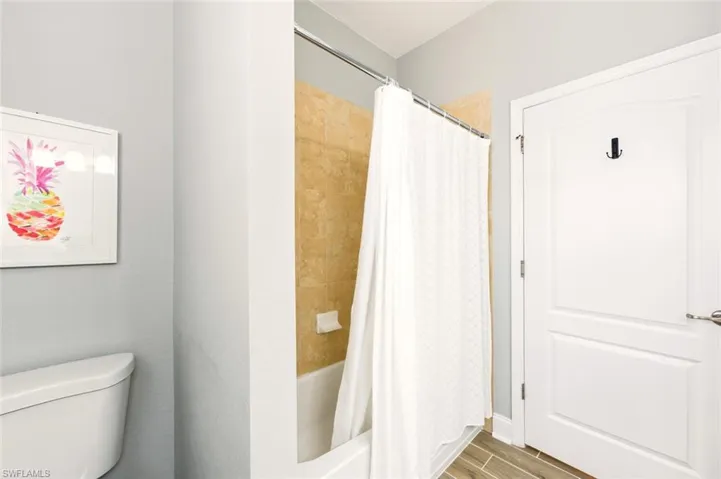 Full bathroom with shower / bathtub combination with curtain and wood tiled floors