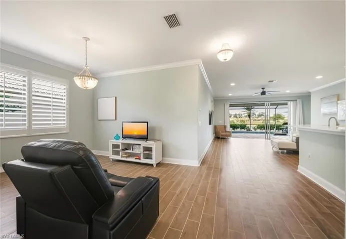 Living room with wood tiled floors, a ceiling fan, and ornamental molding