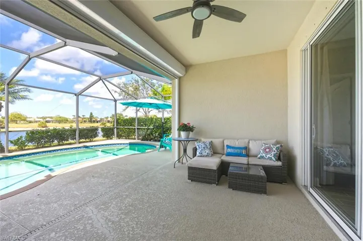 Outdoor pool with outdoor lounge area, a sunroom, glass enclosure, a patio, and a water view
