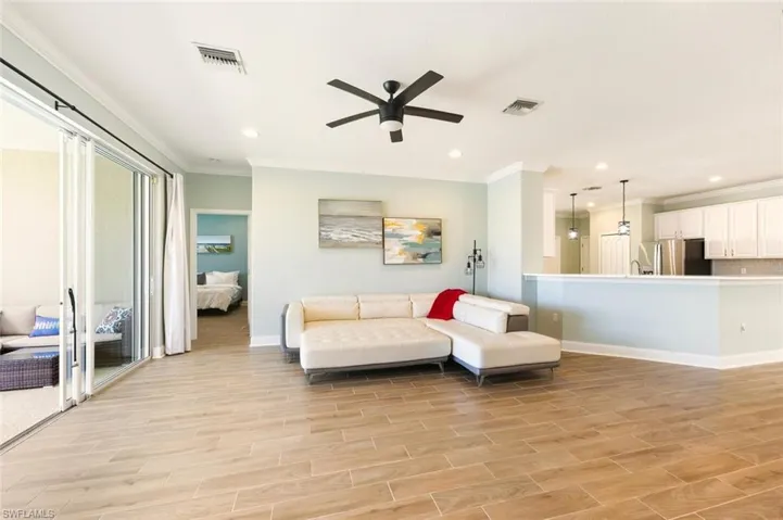 Living room featuring wood tile floors, ornamental molding, a ceiling fan, and recessed lighting