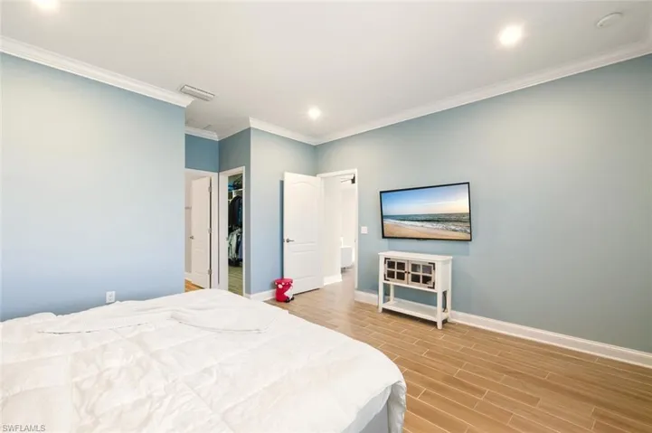 Bedroom with wood tile floors, crown molding, a spacious closet, and recessed lighting