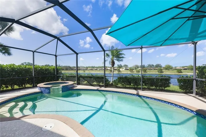 Relaxing pool / spa featuring a sunroom, glass enclosure, and a water view