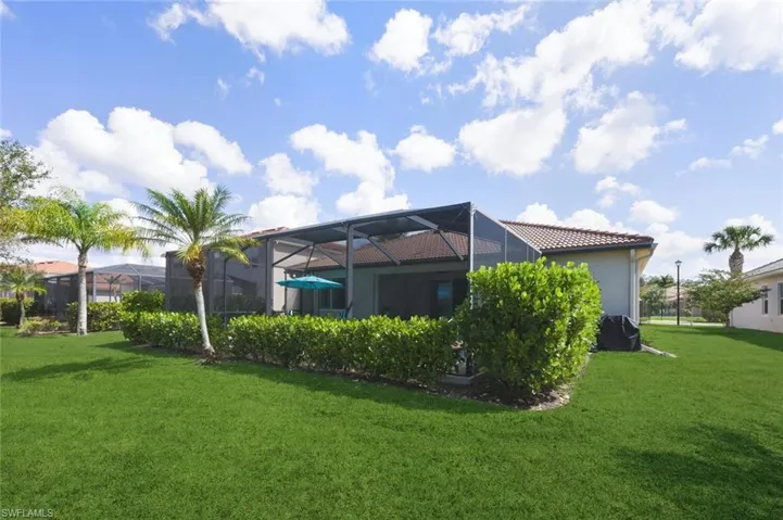 Back of house featuring a sunroom, glass enclosure, a lawn, a tile roof, and stucco siding