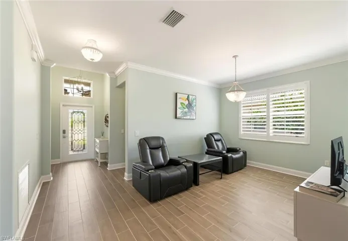 Living area with a chandelier, crown molding, and wood tiled floors