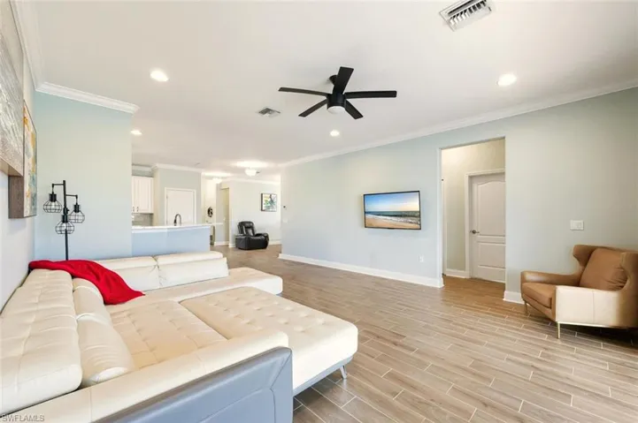 Living area featuring wood tiled floors, recessed lighting, ornamental molding, and ceiling fan