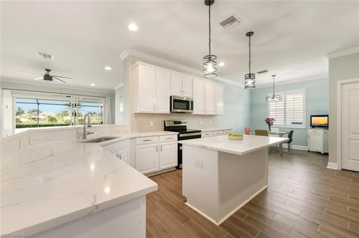 Kitchen featuring a kitchen island, white cabinets, tiled floors, plenty of natural light, and crown molding