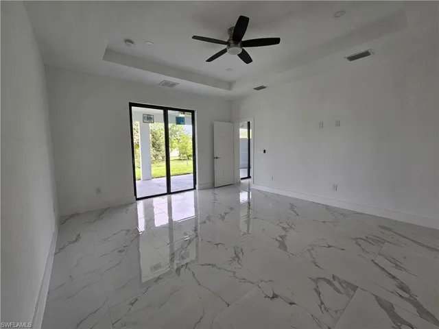 Tiled spare room featuring ceiling fan and a raised ceiling