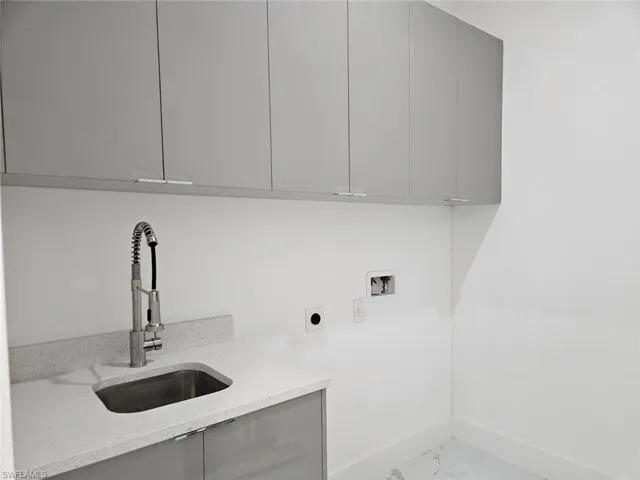 Clothes washing area featuring hookup for an electric dryer, sink, cabinets, hookup for a washing machine, and light tile patterned floors