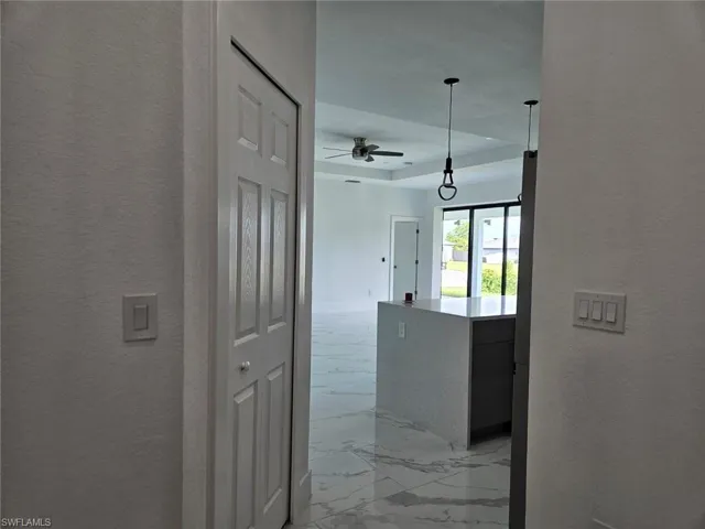 Corridor featuring light tile patterned floors and a tray ceiling