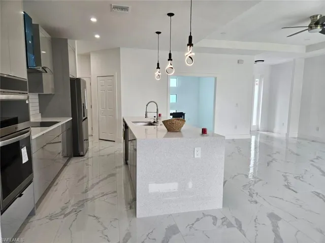 Kitchen featuring appliances with stainless steel finishes, light tile patterned floors, pendant lighting, and sink