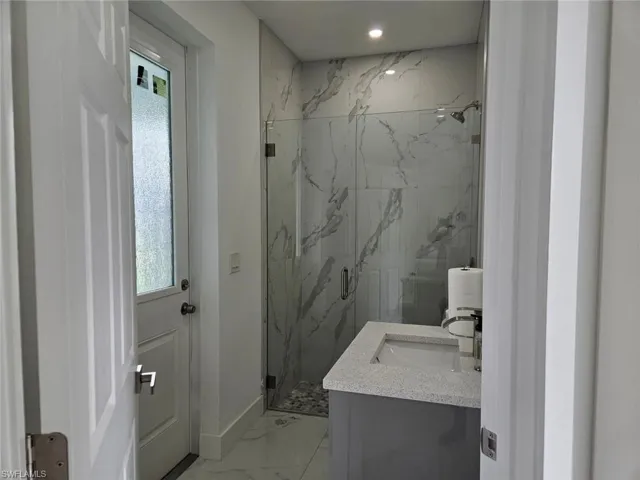 Bathroom with tile patterned flooring, vanity, and a tile shower