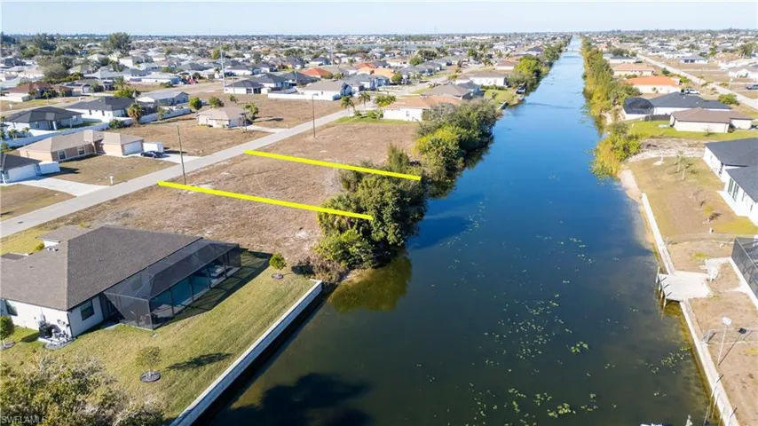 Aerial perspective of suburban area with property parcel outlined and a large body of water