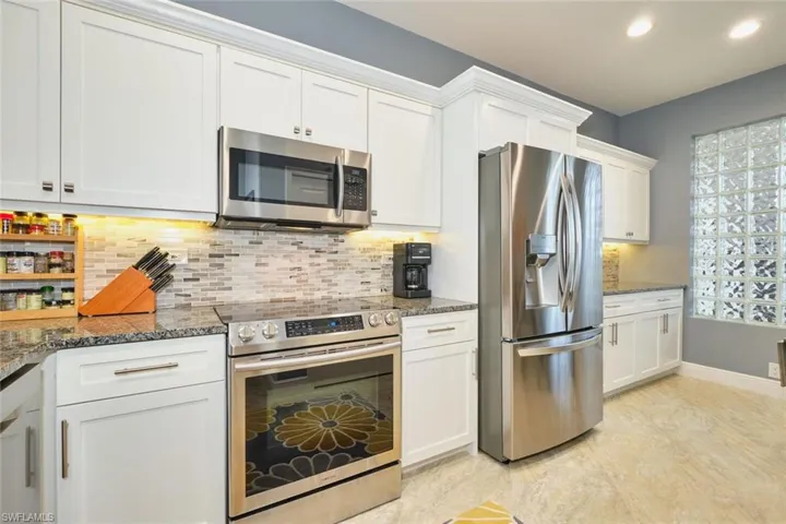 Kitchen featuring appliances with stainless steel finishes, white cabinets, dark stone countertops, tasteful backsplash, and recessed lighting
