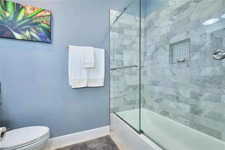 Bathroom featuring shower / bath combination with glass door and baseboards