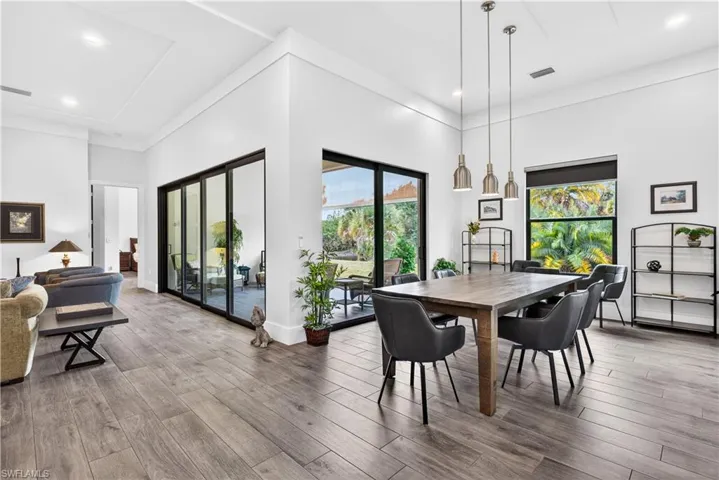 Dining space with light wood finished floors, healthy amount of natural light, recessed lighting, and a high ceiling