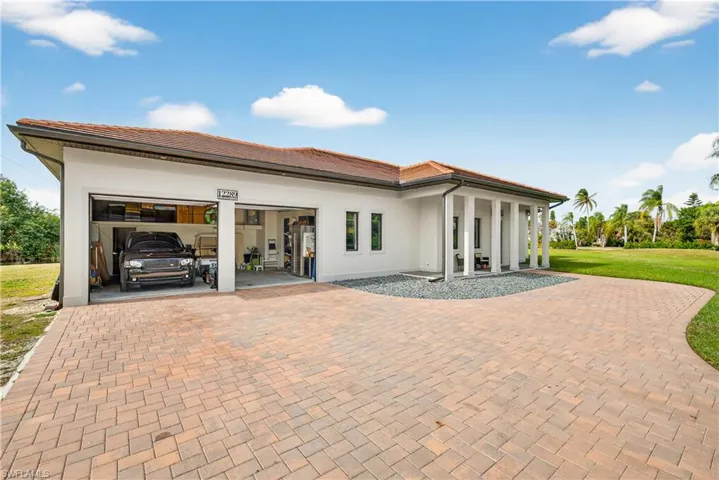 Front of property with decorative driveway, an attached garage, stucco siding, a yard, and a tile roof