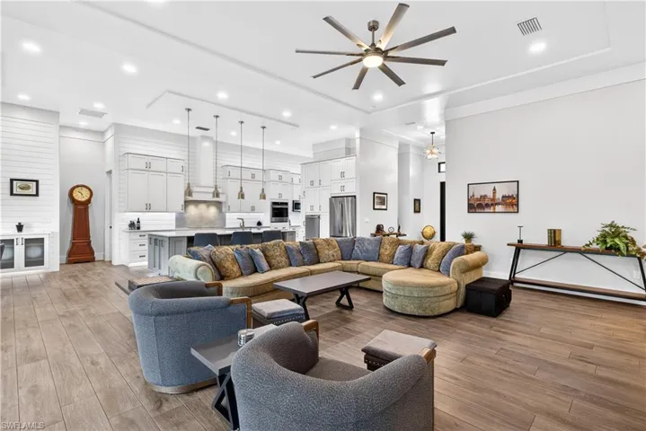 Living room with recessed lighting, a ceiling fan, light wood-type flooring, and a towering ceiling