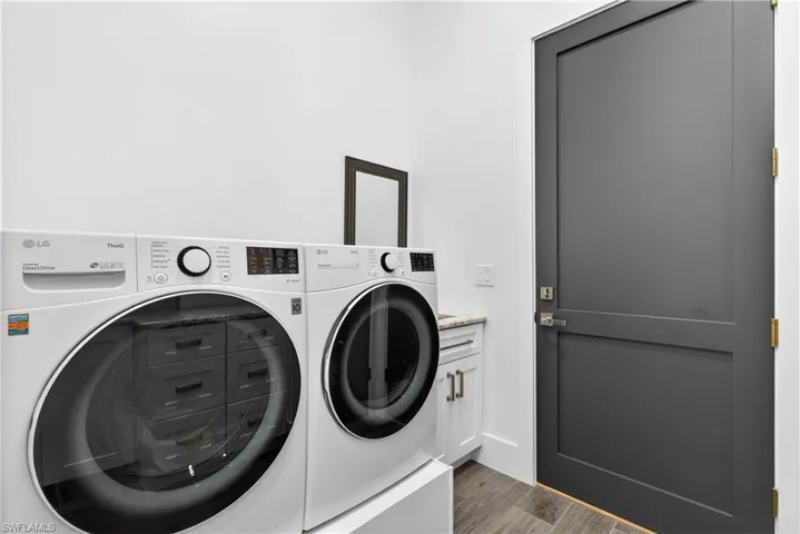 Laundry area with washing machine and clothes dryer, dark wood-style flooring, and cabinet space