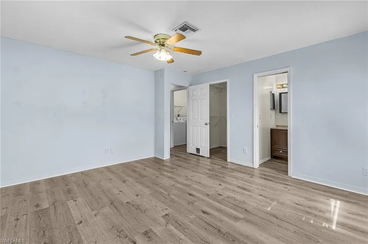 Unfurnished bedroom with light hardwood / wood-style flooring, ceiling fan, a spacious closet, connected bathroom, and a closet