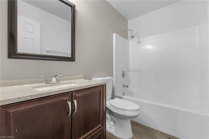 Full bathroom with bathing tub / shower combination, toilet, vanity, and hardwood / wood-style flooring