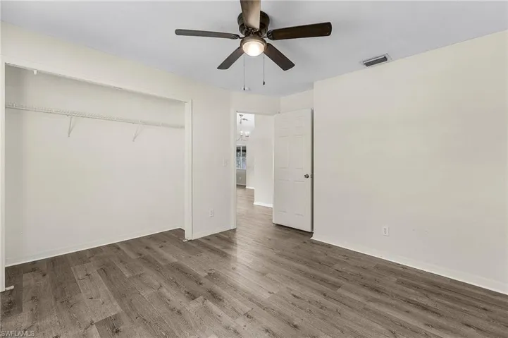 Unfurnished bedroom featuring hardwood / wood-style floors, a closet, and ceiling fan