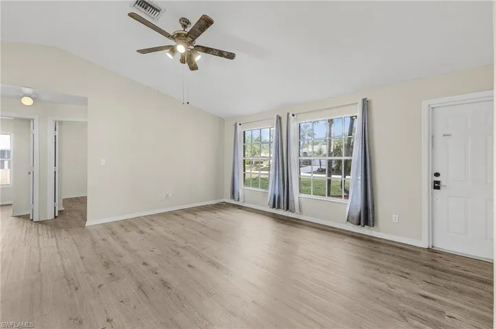 Unfurnished living room with ceiling fan, light hardwood / wood-style floors, and vaulted ceiling