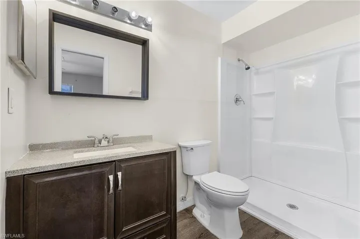 Bathroom featuring vanity, hardwood / wood-style flooring, toilet, and walk in shower
