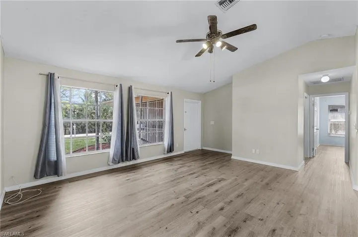Spare room featuring light hardwood / wood-style floors, vaulted ceiling, and ceiling fan