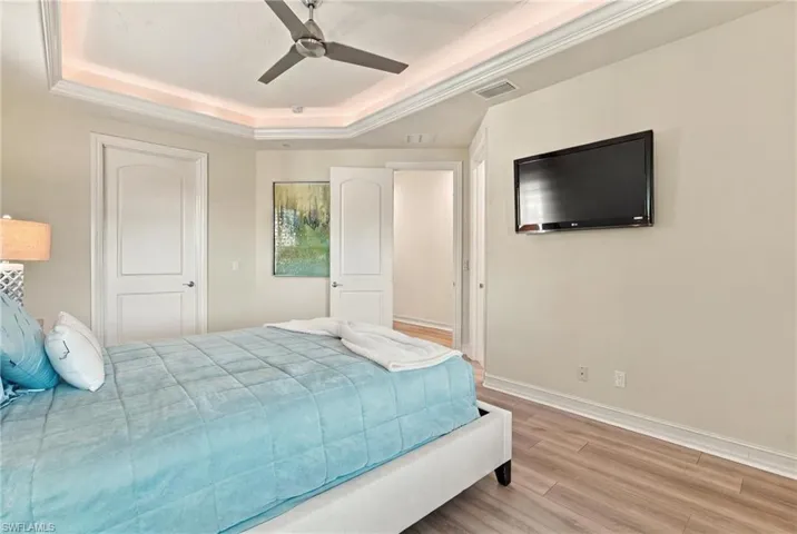 Tray ceiling with recessed accent lighting, brushed nickel ceiling fan, and wood-finish flooring