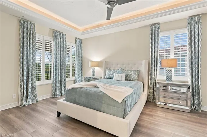 Tray ceiling with recessed lighting, wood-finish flooring, and white plantation shutters