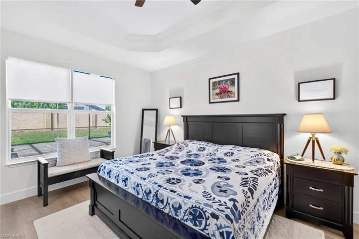 Bedroom featuring light wood-type flooring, crown molding, a raised ceiling, and a ceiling fan