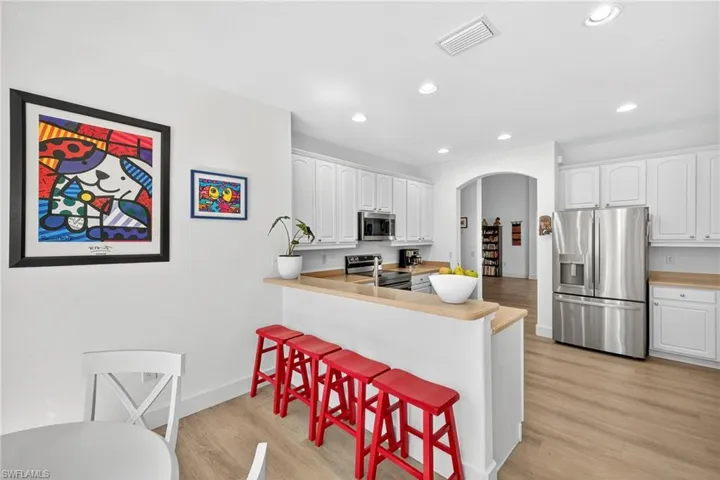Kitchen featuring white cabinets, stainless steel appliances, arched walkways, and recessed lighting