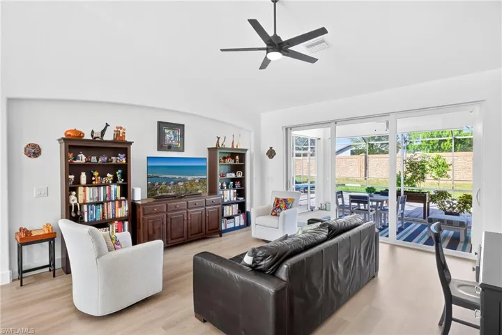 Living room featuring light wood-type flooring, a ceiling fan, and vaulted ceiling