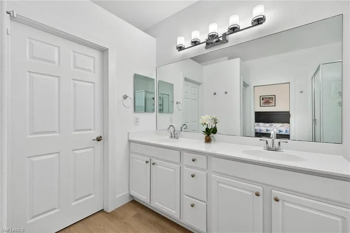 Bathroom with double vanity, light wood-type flooring, a shower stall, and connected bathroom