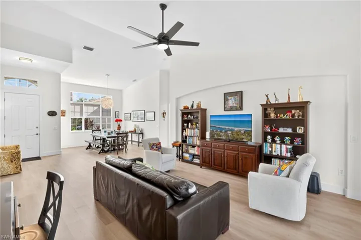 Living area featuring light wood-style flooring, vaulted ceiling, and ceiling fan