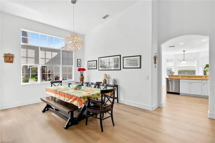 Dining area with light wood-type flooring, a towering ceiling, and arched walkways