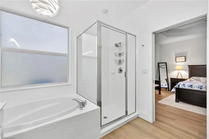 Bathroom with a stall shower, light wood-type flooring, a garden tub, and connected bathroom
